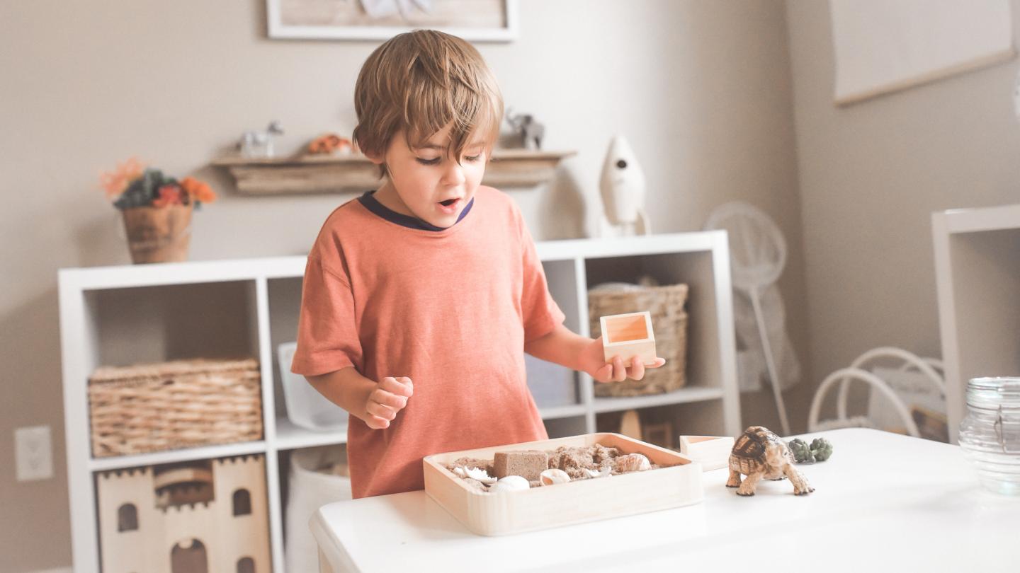 Child playing with sand on a table